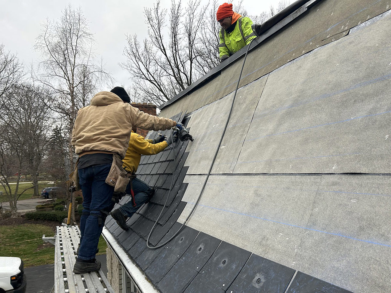 Roofers laying shingles on sloped roof